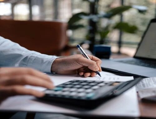 Person using a calculator and pen to budget