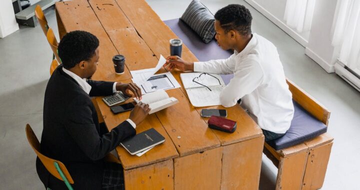 Two business professionals reviewing financial charts and documents to discuss a Corporate Division I Proposal.