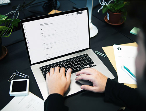 close up of male hands typing on a keyboard surrounded by papers