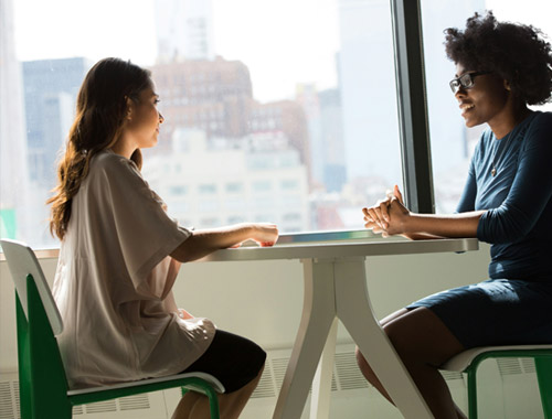 two friends sitting at a table talking